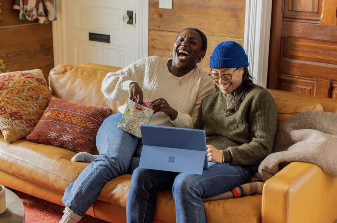 two women laughing together on a sofa